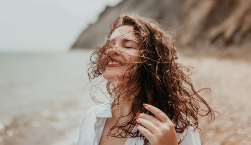 A woman with her hair blowing in the wind on the beach.