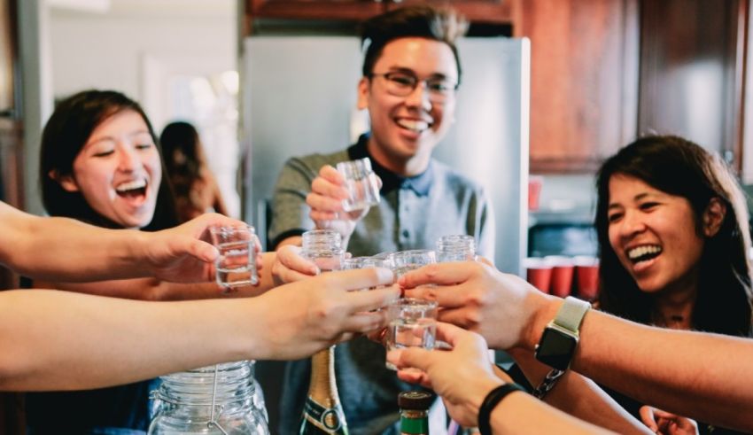 A group of people toasting glasses in a kitchen.