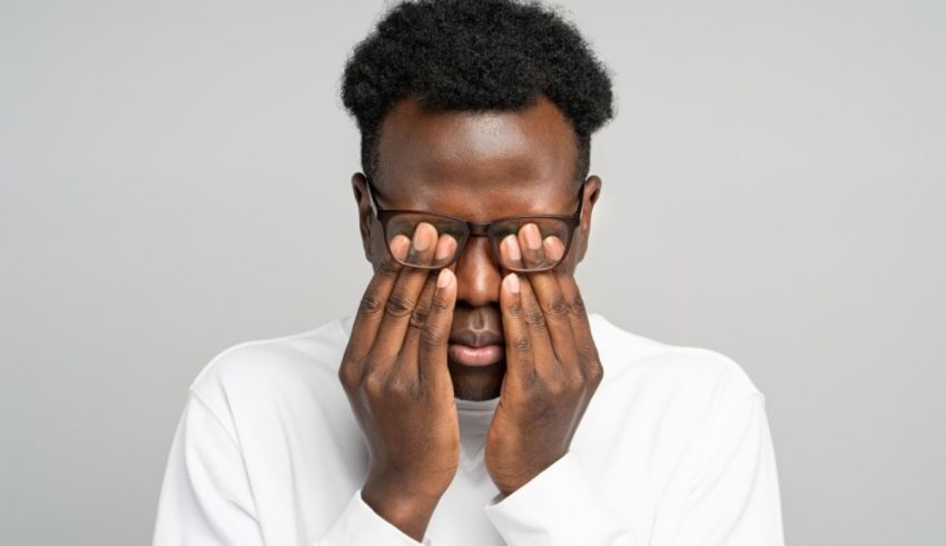 A black man covering his eyes with his hands.