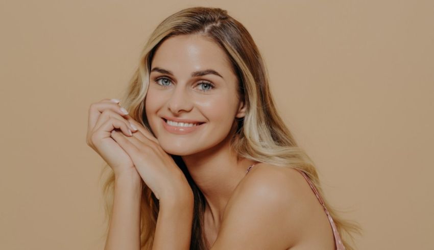 A beautiful blonde woman posing on a beige background.