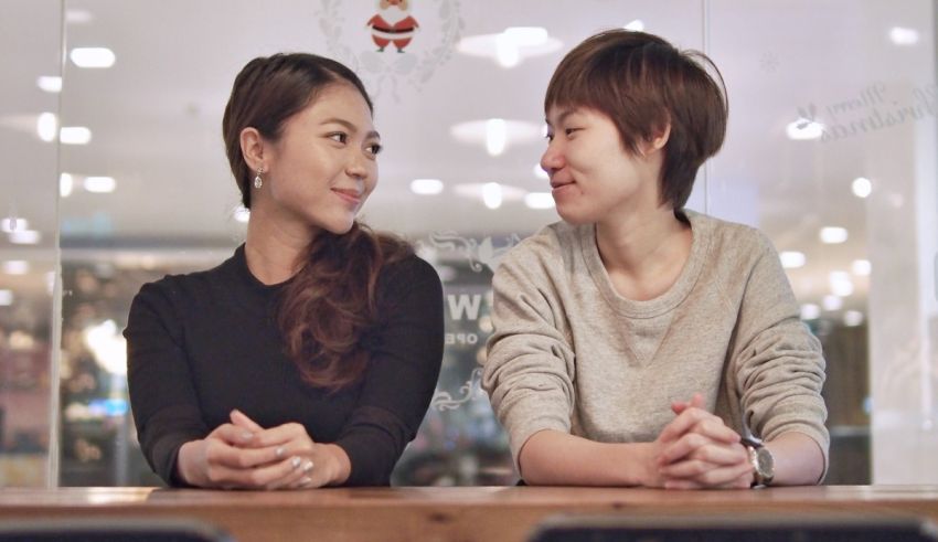 Two asian women sitting together at a table.