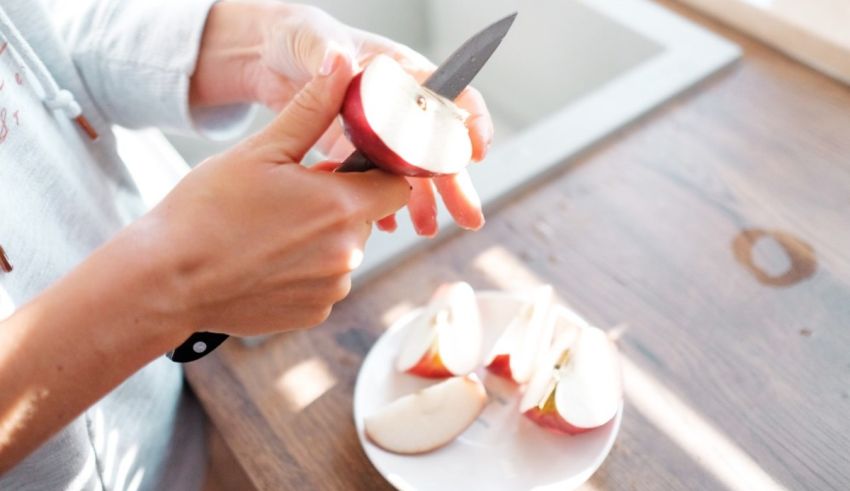 A woman cutting an apple with a knife.