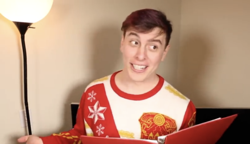 A man in a red sweater holding a book.