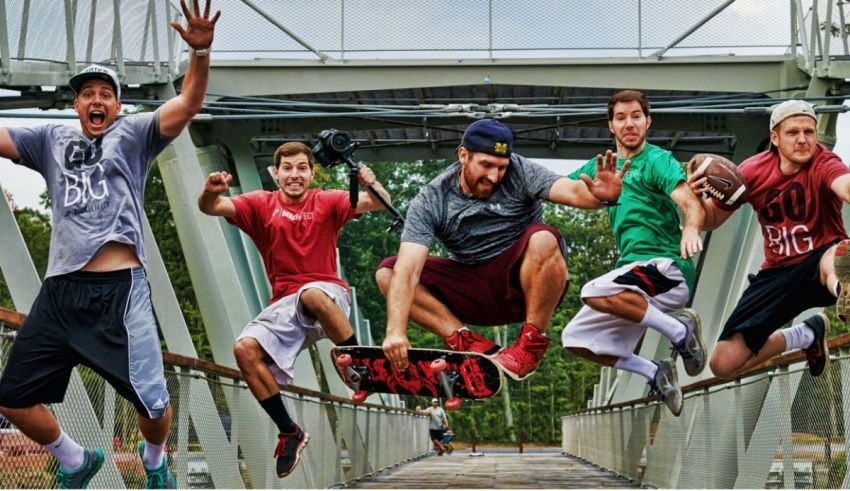 A group of men jumping on a bridge with skateboards.