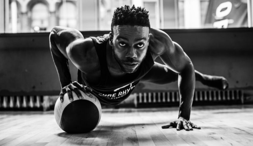 A black and white photo of a man doing push ups with a ball.