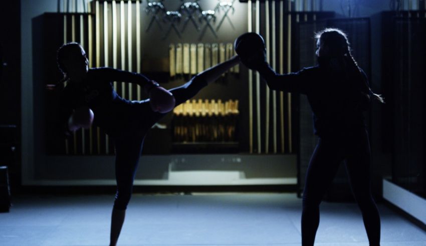 Two women practicing martial arts in a dark room.