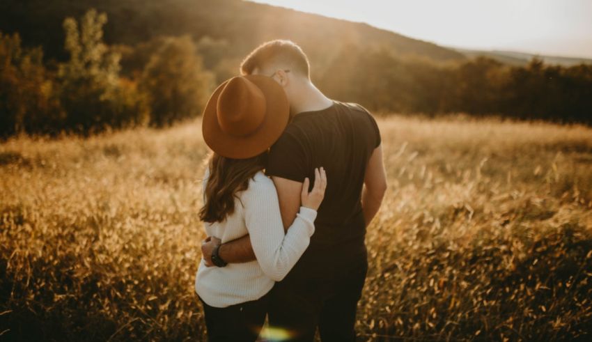 A couple embracing in a field at sunset.
