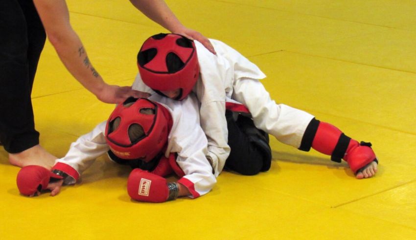 A child is laying down on a yellow mat in a karate class.