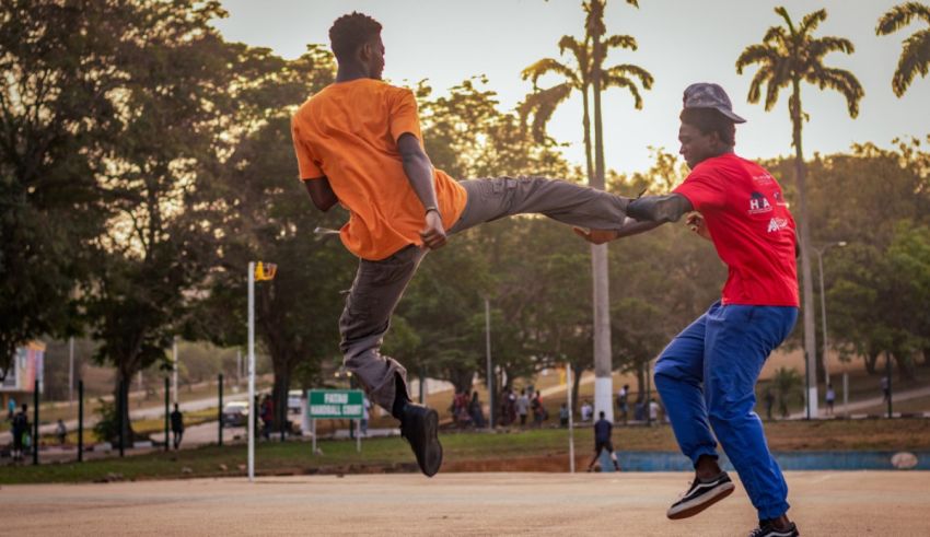 Two young men doing a kick in a park.