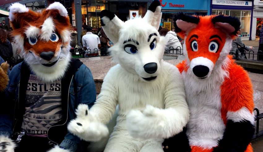 Three fox mascots sitting on a bench.