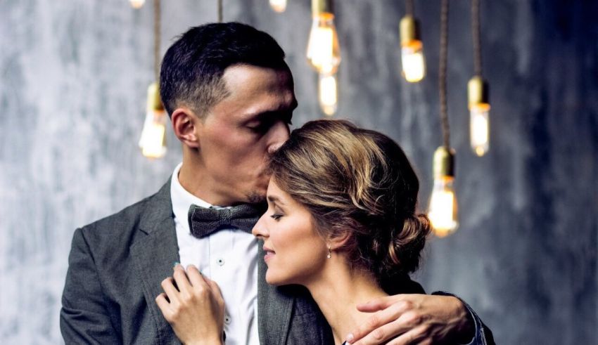 A man and woman hugging in front of light bulbs.