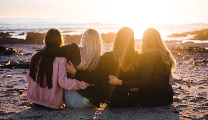 A group of friends sitting on the beach at sunset.