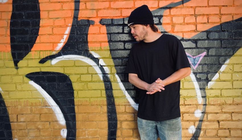 A man leaning against a brick wall with graffiti on it.