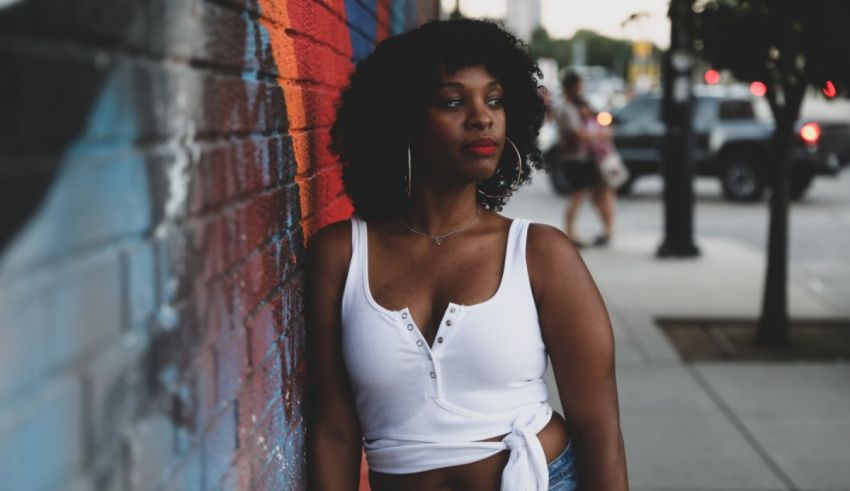 A black woman leaning against a wall.