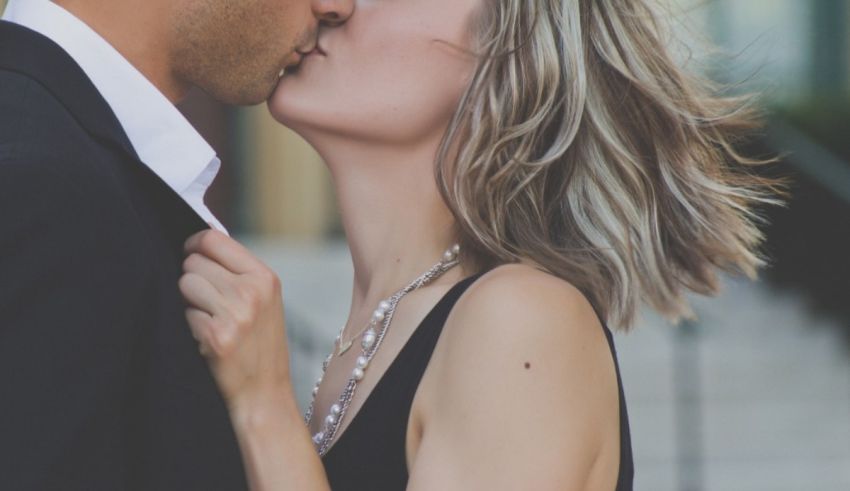 A man and woman kissing in front of a building.