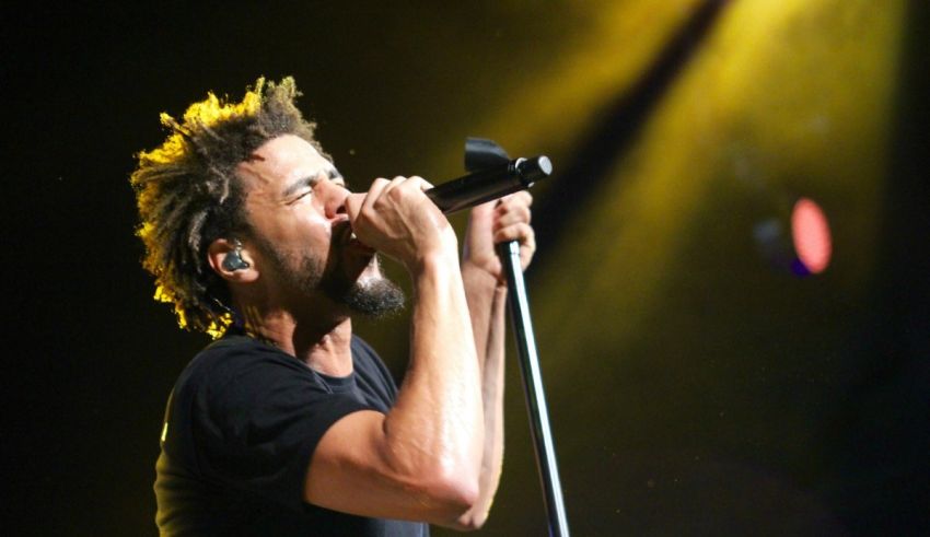 A man with dreadlocks singing into a microphone.