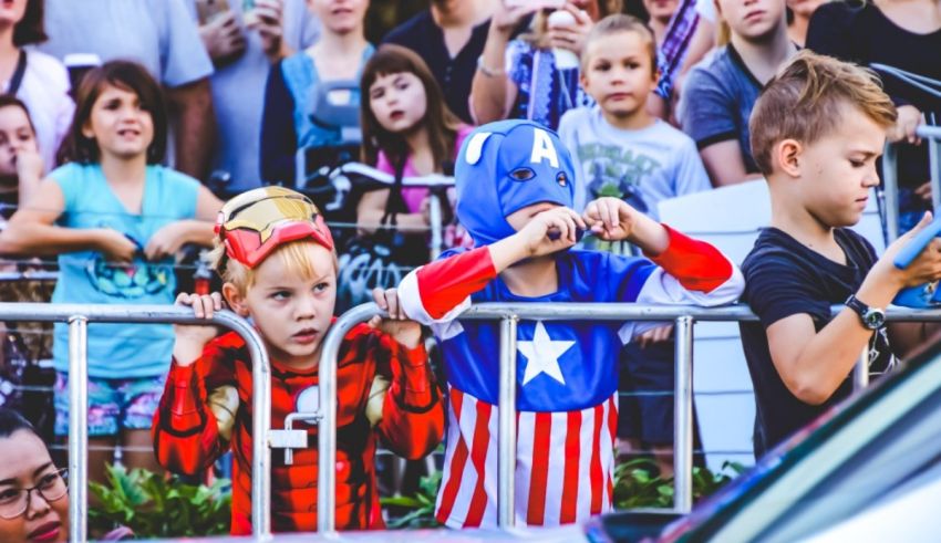 A group of children dressed up as captain america in front of a crowd.