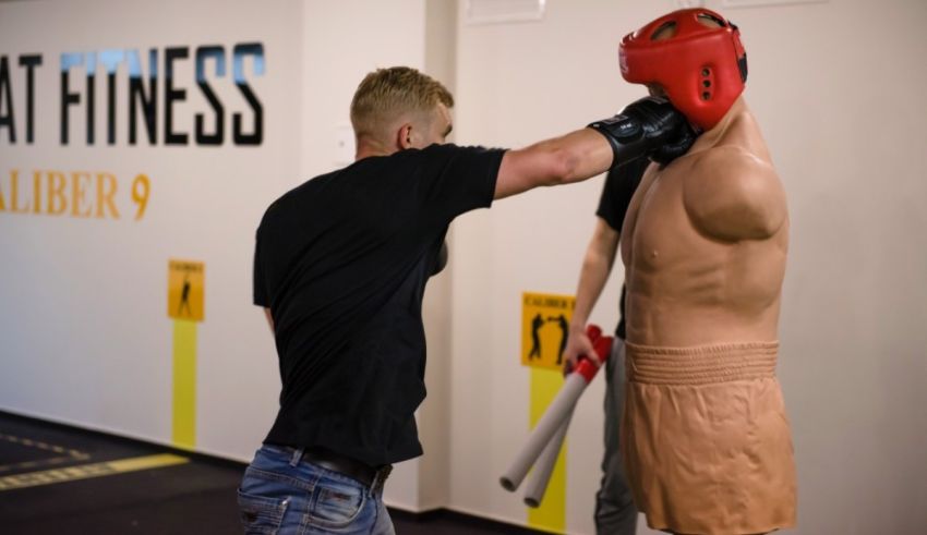 A man is punching a mannequin in a gym.