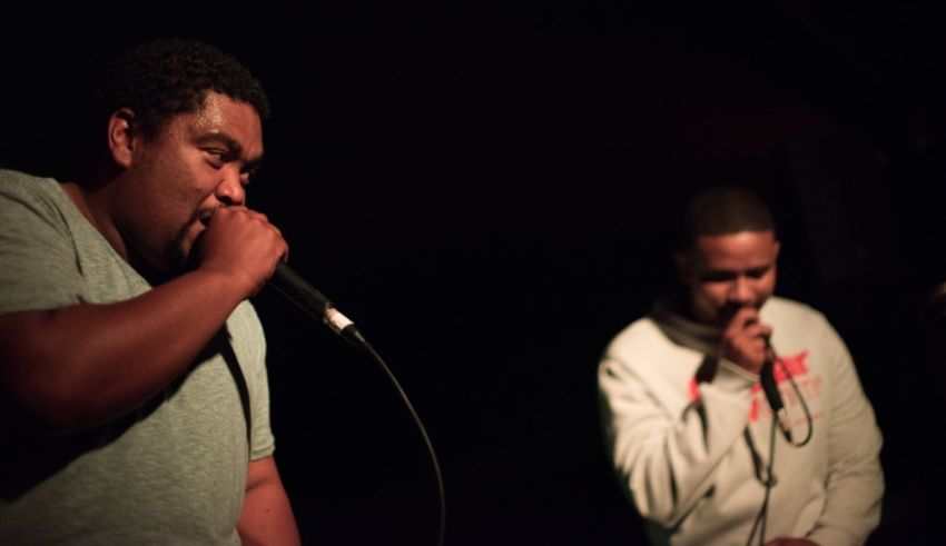 Two men singing into a microphone in front of a crowd.