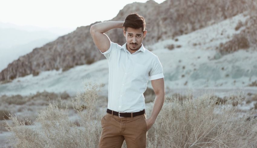 A man in a white shirt and tan pants standing in the desert.