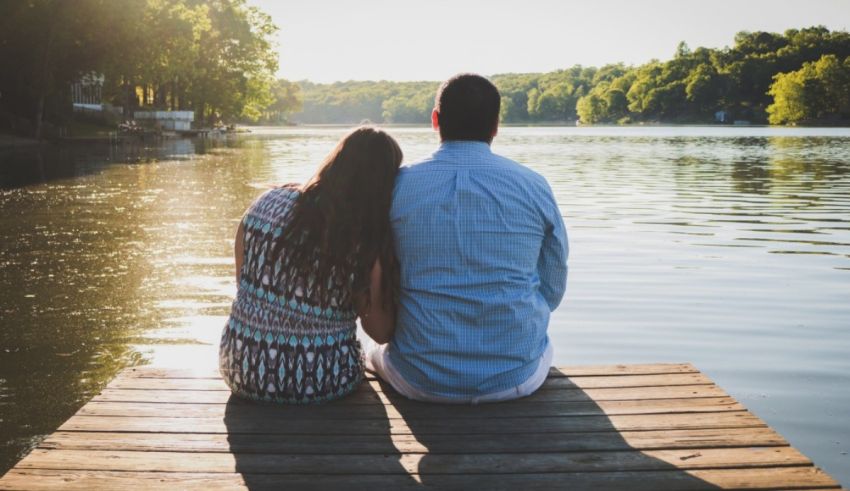 A couple sitting on a dock overlooking a lake.
