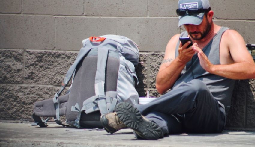 A man sitting on the ground looking at his phone.