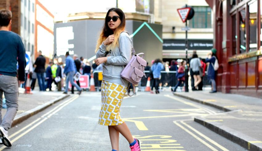 A woman in a yellow patterned skirt walking down the street.
