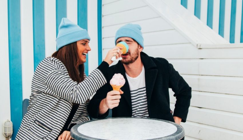 A man and woman eating ice cream at a table.