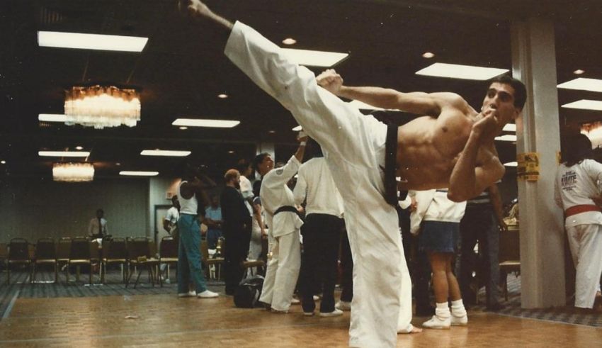 A man doing karate in a room full of people.