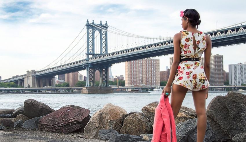 A woman in a floral dress looking at the manhattan bridge.