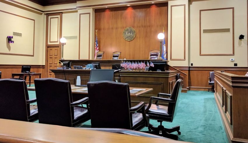 An empty courtroom with a desk and chairs.