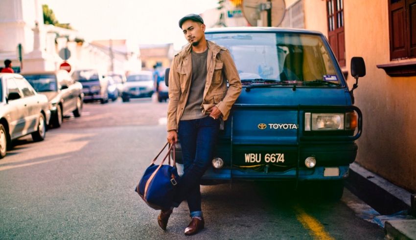 A man leaning on the side of a blue van.