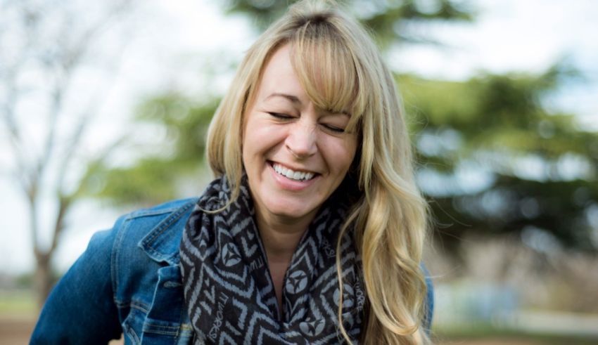 A woman is smiling while holding a scarf.