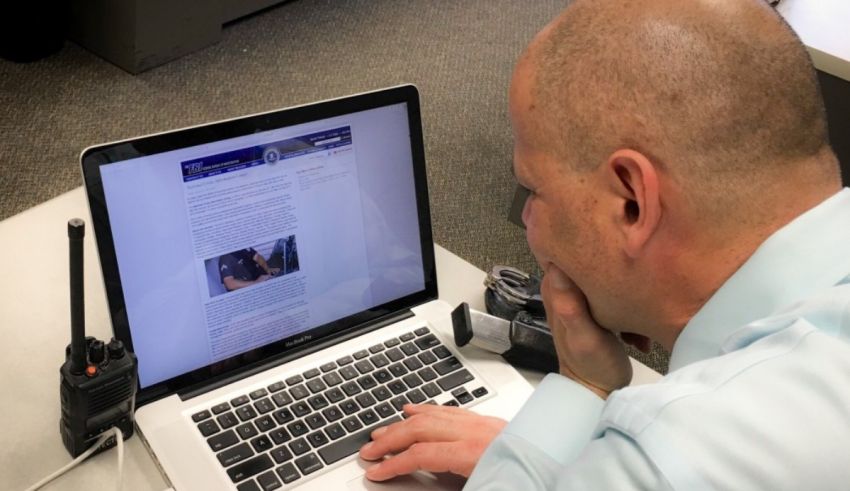 A man in a blue shirt is looking at a laptop computer.