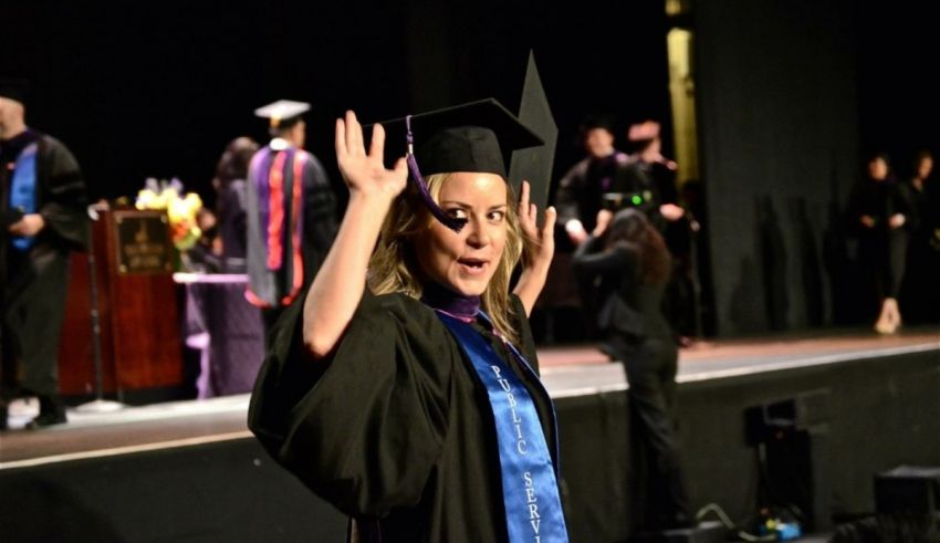 A woman in a graduation gown waving her hands in the air.