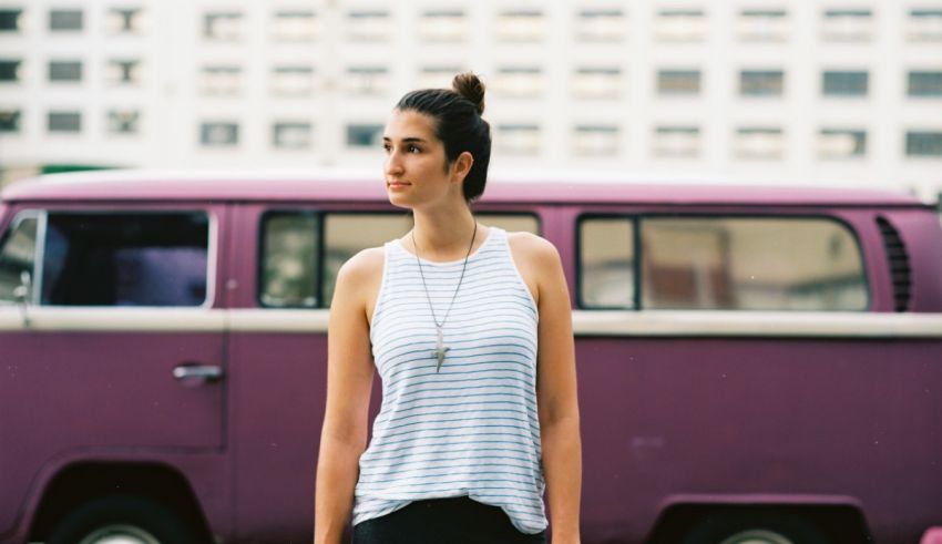A young woman standing in front of a purple vw bus.