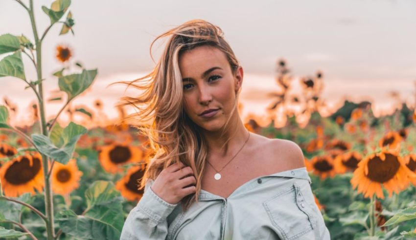 A woman standing in a sunflower field at sunset.