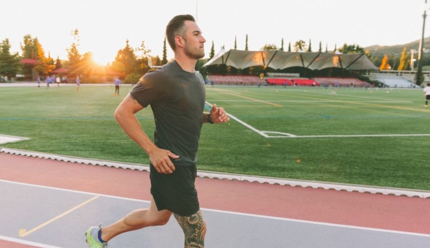 A man jogging on a track at sunset.