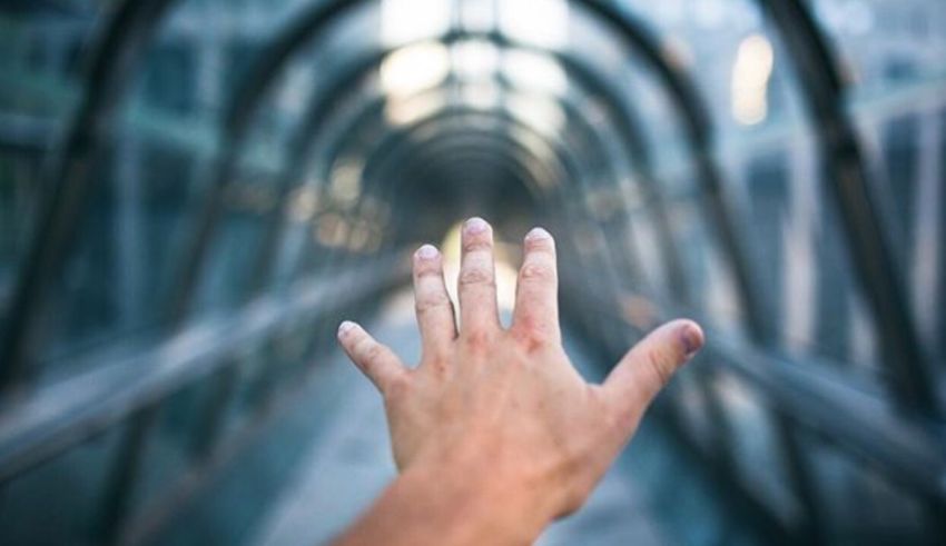 A person's hand reaching out of a glass walkway.