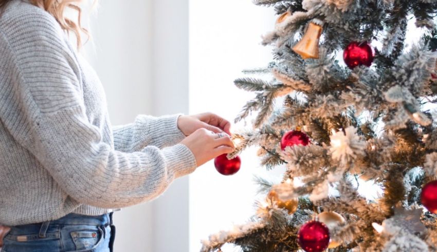 A woman is putting ornaments on a christmas tree.