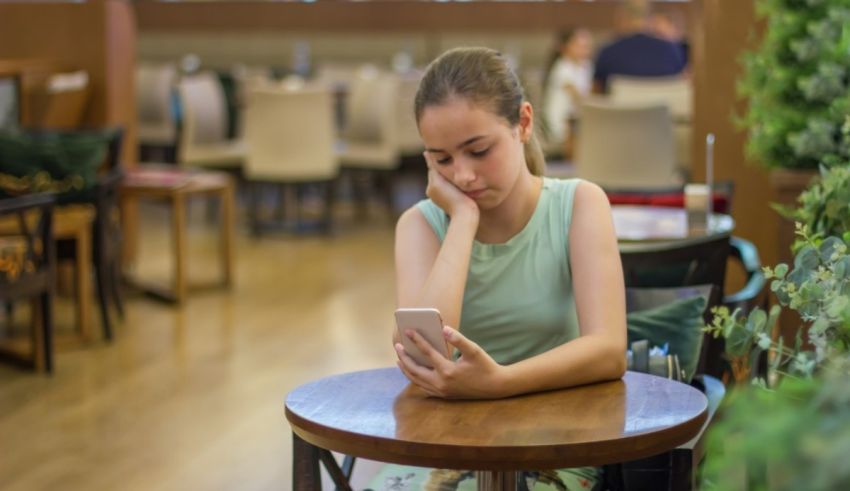 A girl sitting at a table looking at her phone.