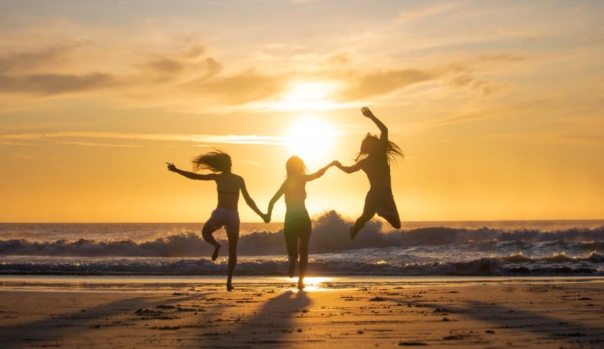 Three friends jumping on the beach at sunset.