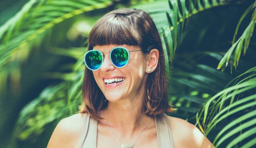 A woman wearing sunglasses in front of a palm tree.