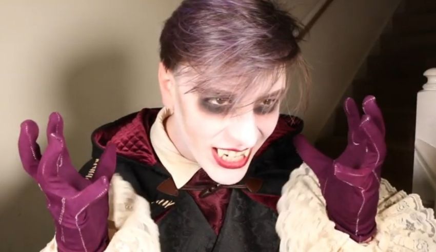 A man dressed as a vampire with purple gloves.