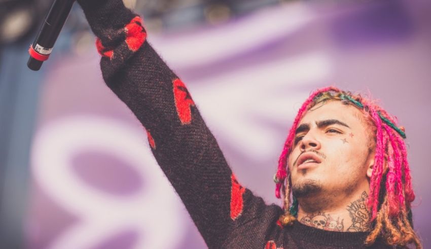 A man with pink dreadlocks holding up a microphone.