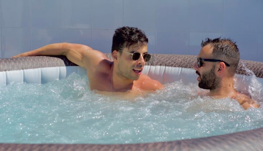 Two men sitting in an inflatable hot tub.