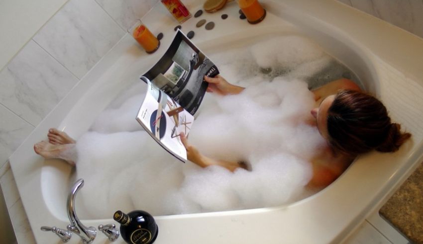 A woman reading a magazine in a bubble bath.