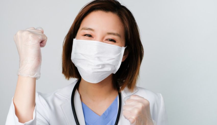 Asian female doctor wearing a surgical mask and showing her fist.