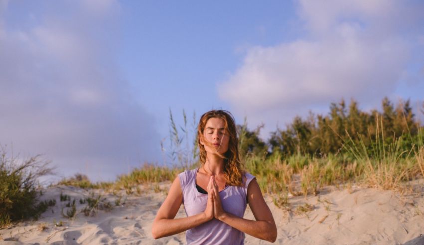A woman is doing yoga in the sand on a beach.