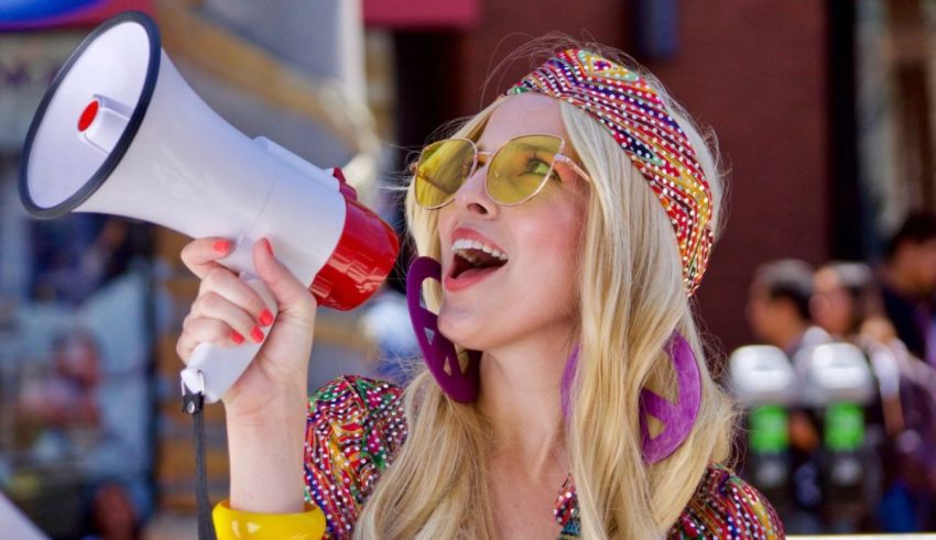 A woman in a colorful outfit shouting into a megaphone.